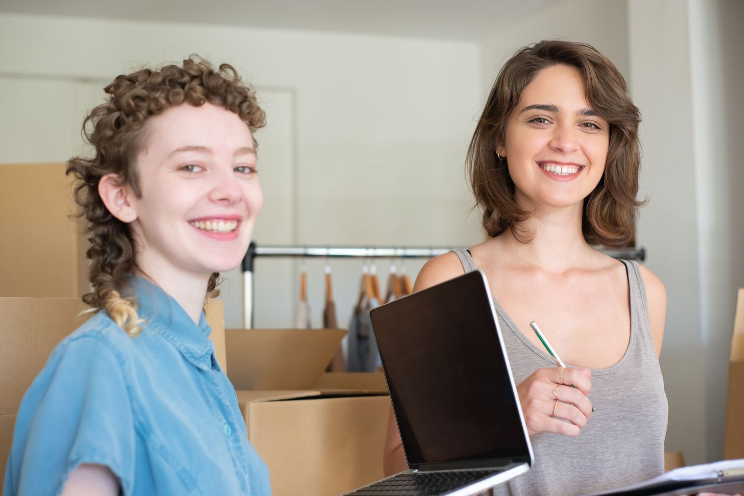 Two small business owners smiling together with a laptop in their shop.