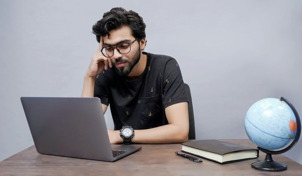 Man sits slightly annoyed waiting for his computer to load.